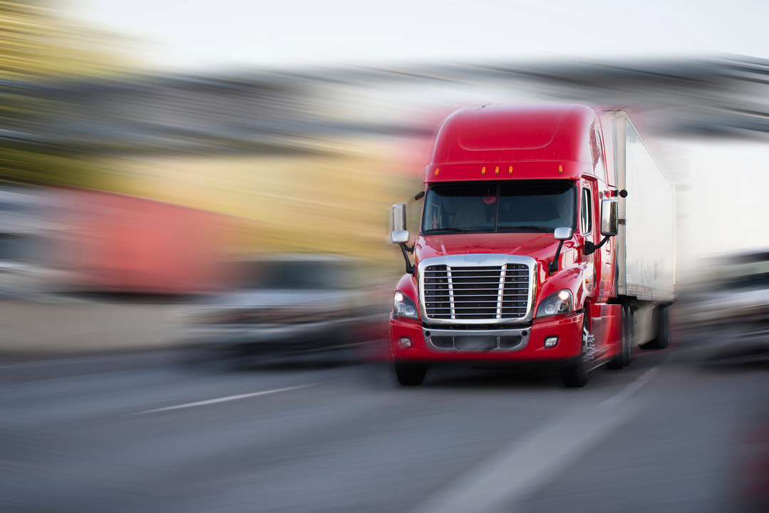 A red semi truck driving on the highway.