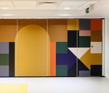A bright hospital wall featuring multicoloured shapes.