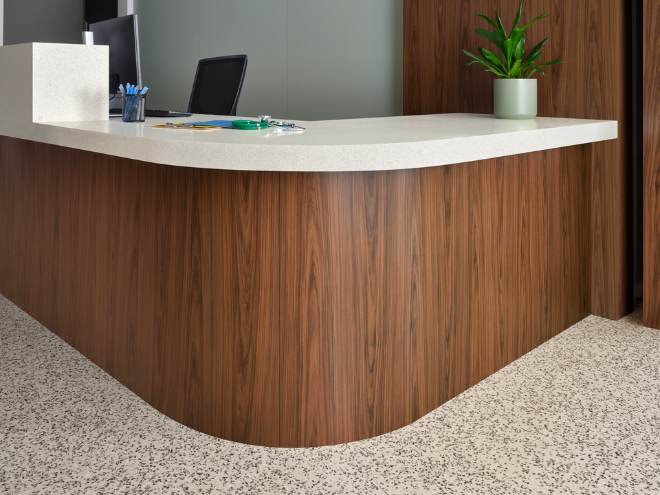 A front desk with woodgrain casework and a solid white countertop.