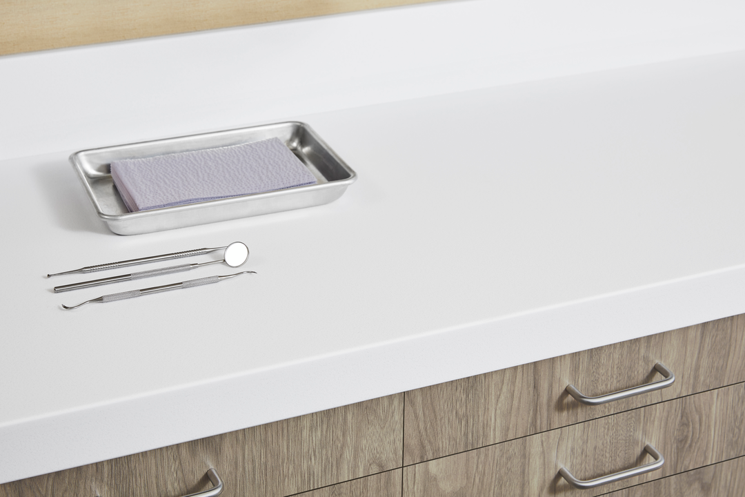 A healthcare countertop and cabinet duo, with woodgrain cabinetry and white countertops.