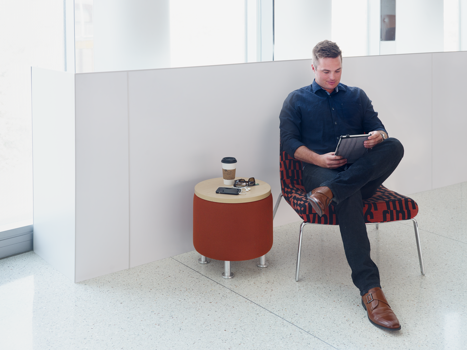 A man sitting in a chair reading on a tablet