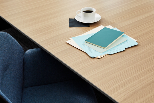 A woodgrain desk with paperwork and a coffee