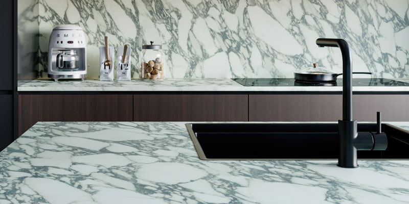 A home kitchen with stone look countertops and woodgrain cabinets.
