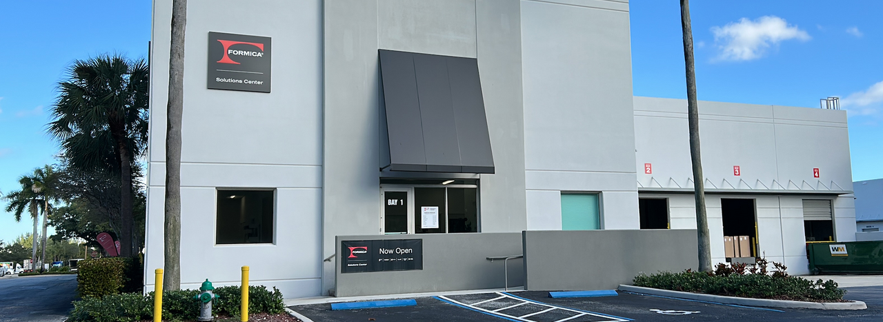 The outside of a gray building with palm trees.